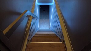 Eine Treppe mit Holzboden und weißen Geländern, die zu einem dunklen Raum oben führt.