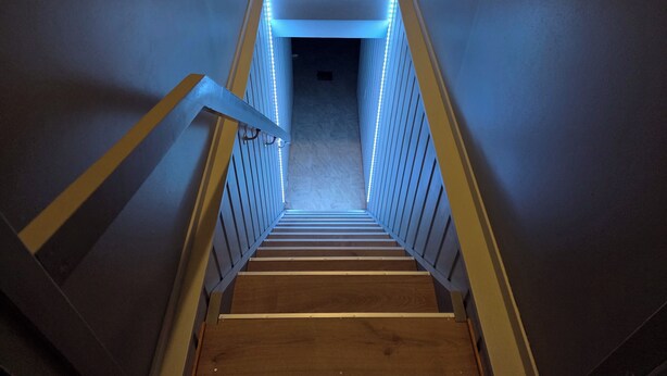 Una escalera de madera con barandillas blancas que conduce a una habitación oscura al final.