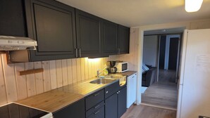 Una cocina con armarios oscuros, una encimera de madera, una estufa blanca, un fregadero y un microondas.