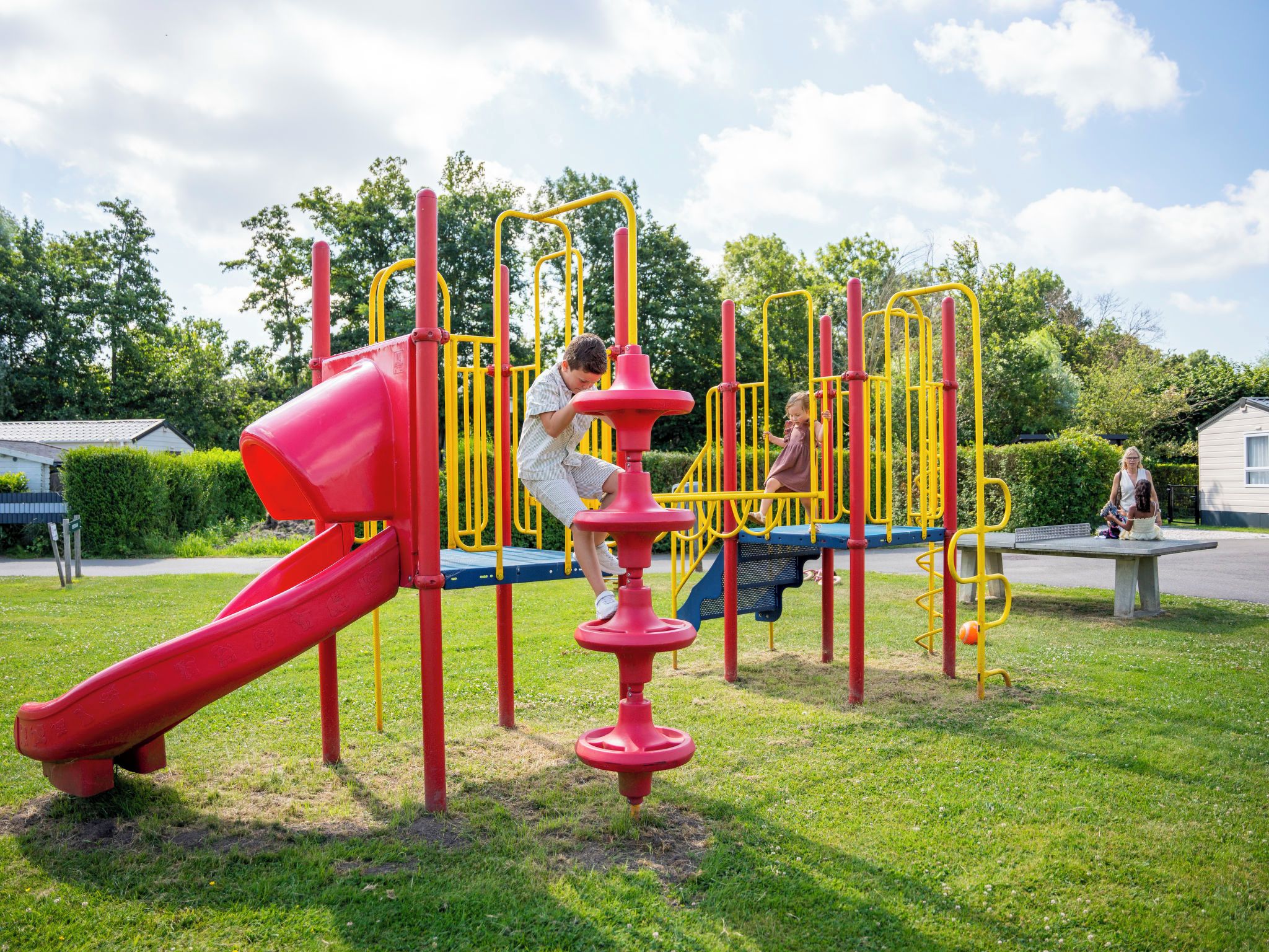 Un parc infantil amb un tobogan vermell i elements per escalar.