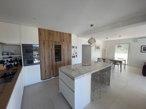 Une cuisine moderne dotée d’un îlot central, de meubles en bois et d’un coin repas avec une table et des chaises.