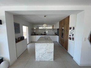 A modern kitchen with a marble island, wooden cabinets, and a pendant light. - Contemporary Villa & Pool (Ajaccio)