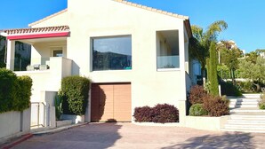 Una casa moderna de dos pisos amb un gran finestral, una porta de garatge i un porxo cobert.