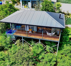 Una casa moderna con una terraza amplia, una hamaca y una piscina.