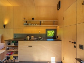 A compact kitchen with wooden cabinets, a sink, and a window with a view of greenery. - Tiny Cabin Sunshine no 21 by Interhome (Kerkwerve)
