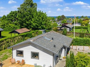 Ein eingeschossiges Haus mit Terrasse, umgeben von üppiger Vegetation und Blick auf das Meer.