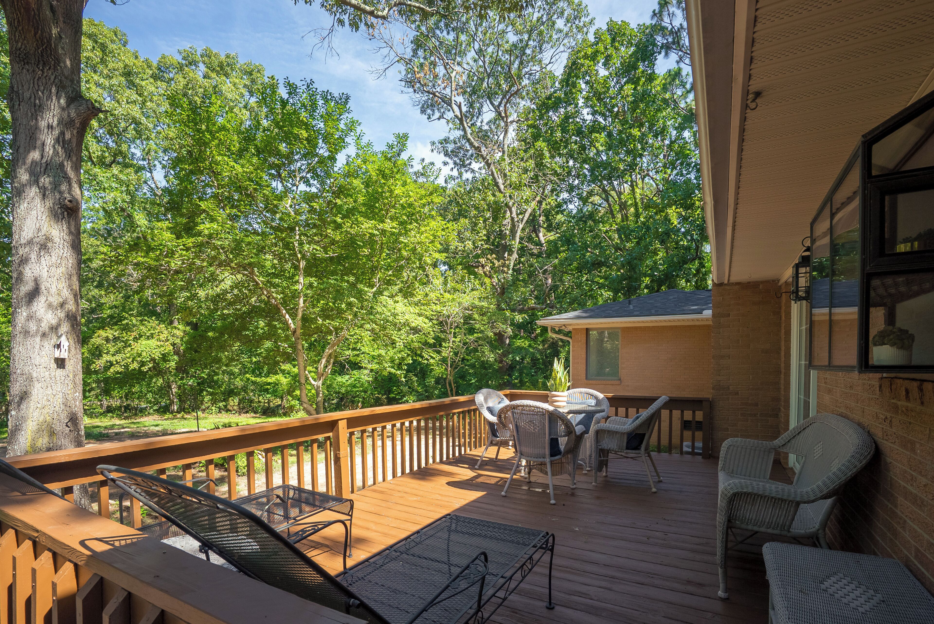 Eine Holzterrasse mit Gartenmöbeln, mit Blick auf ein bewaldetes Gebiet.