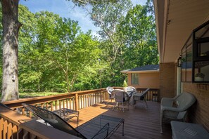 Une terrasse en bois, aménagée avec du mobilier d’extérieur, qui offre une vue sur une zone boisée.