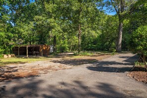 Un terrain de camping avec un sentier de gravier, une structure en bois et de nombreux arbres.