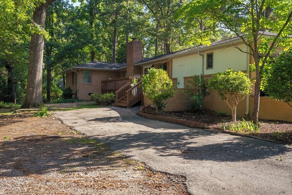 A two-story house with a brick chimney, a front porch, and a driveway leading to the entrance.