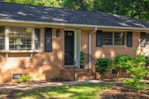 A two-story house with a front porch, a black front door, and a brick exterior.