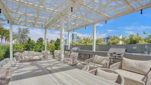 Une terrasse extérieure dotée d’une pergola, d’un espace salon et d’un coin barbecue.