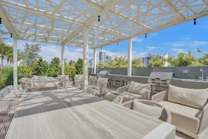 An outdoor patio with a pergola, seating, and a grill area. - Ocean View 1BR with Balcony, Pool & Gym Near Beach (Miami Beach)