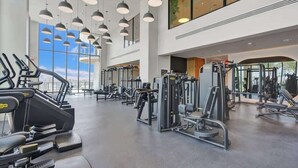 Une salle de sport équipée de tapis de course, d’appareils de musculation et dotée d’une grande fenêtre.