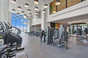 A gym with treadmills, weight machines, and a large window. - Ocean View 1BR with Balcony, Pool & Gym Near Beach (Miami Beach)