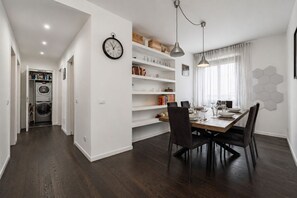 A modern kitchen with a dining area, built-in shelves, and a clock on the wall. - 1 minute's walk from the tram stop for the Duomo (Milan)