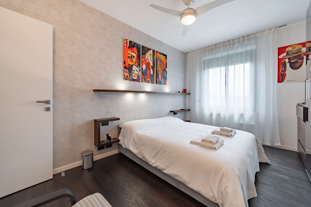 Een moderne hotelkamer met een bed, kunst aan de muur en een plafondventilator.