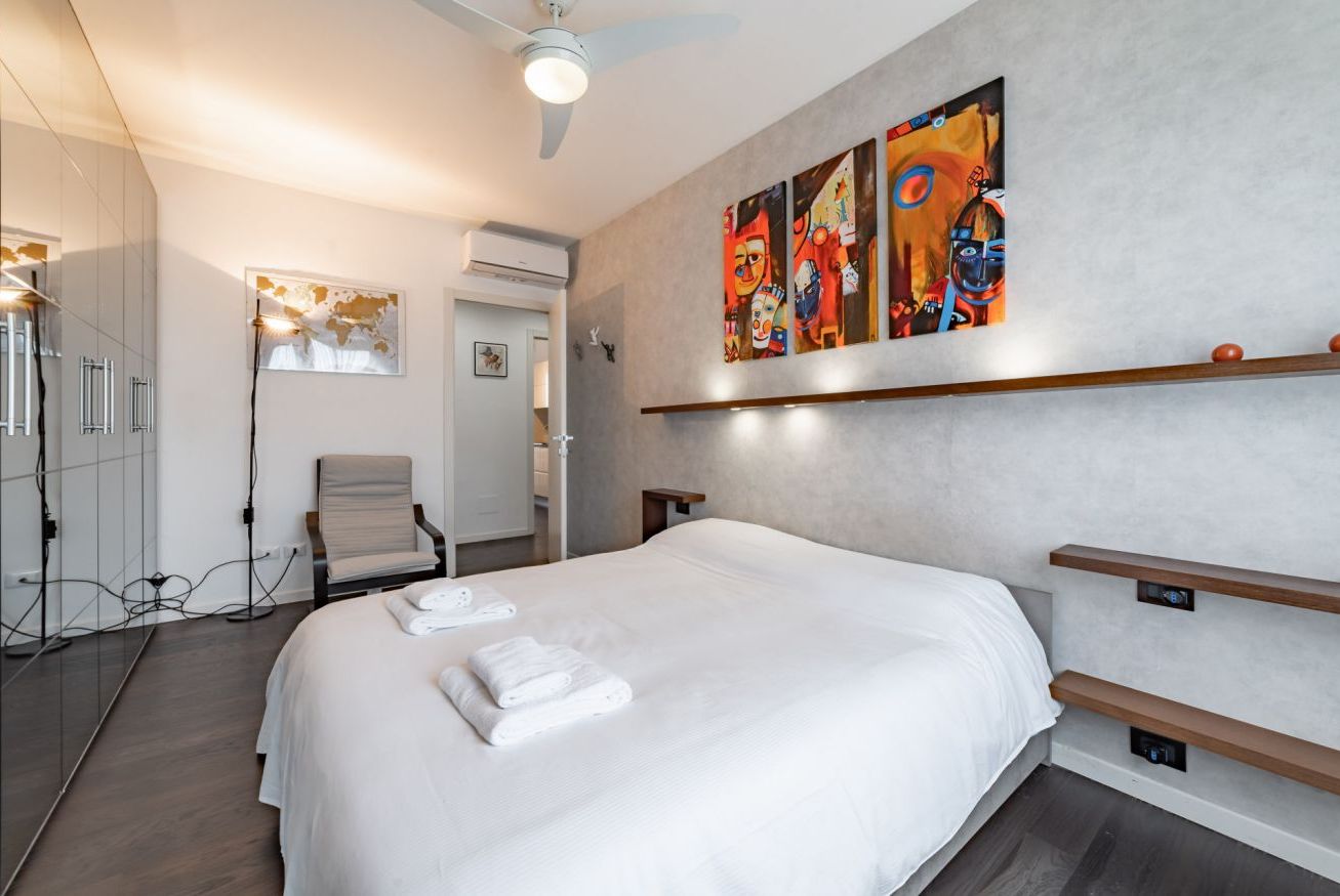 Een moderne hotelkamer met een groot bed, een stoel, een kledingkast en een schilderij aan de muur.