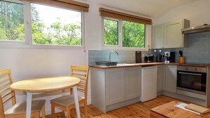 A compact kitchen with a dining table, chairs, a sink, and a stove.