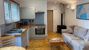 A compact living space with a kitchenette, a sofa, a coffee table, and a map on the wall.