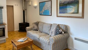 A living room with a sofa, a coffee table, a map, and a painting on the wall.