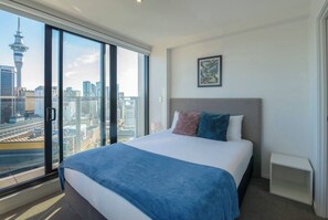 Ein Hotelzimmer mit einem großen Bett, Blick auf die Stadt und einem gerahmten Bild an der Wand.