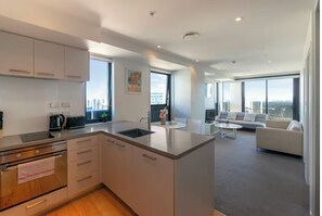 Eine moderne Wohnung mit Küche, Essbereich und Wohnzimmer. Sie verfügt über große Fenster, Blick auf die Stadt und einen Balkon.