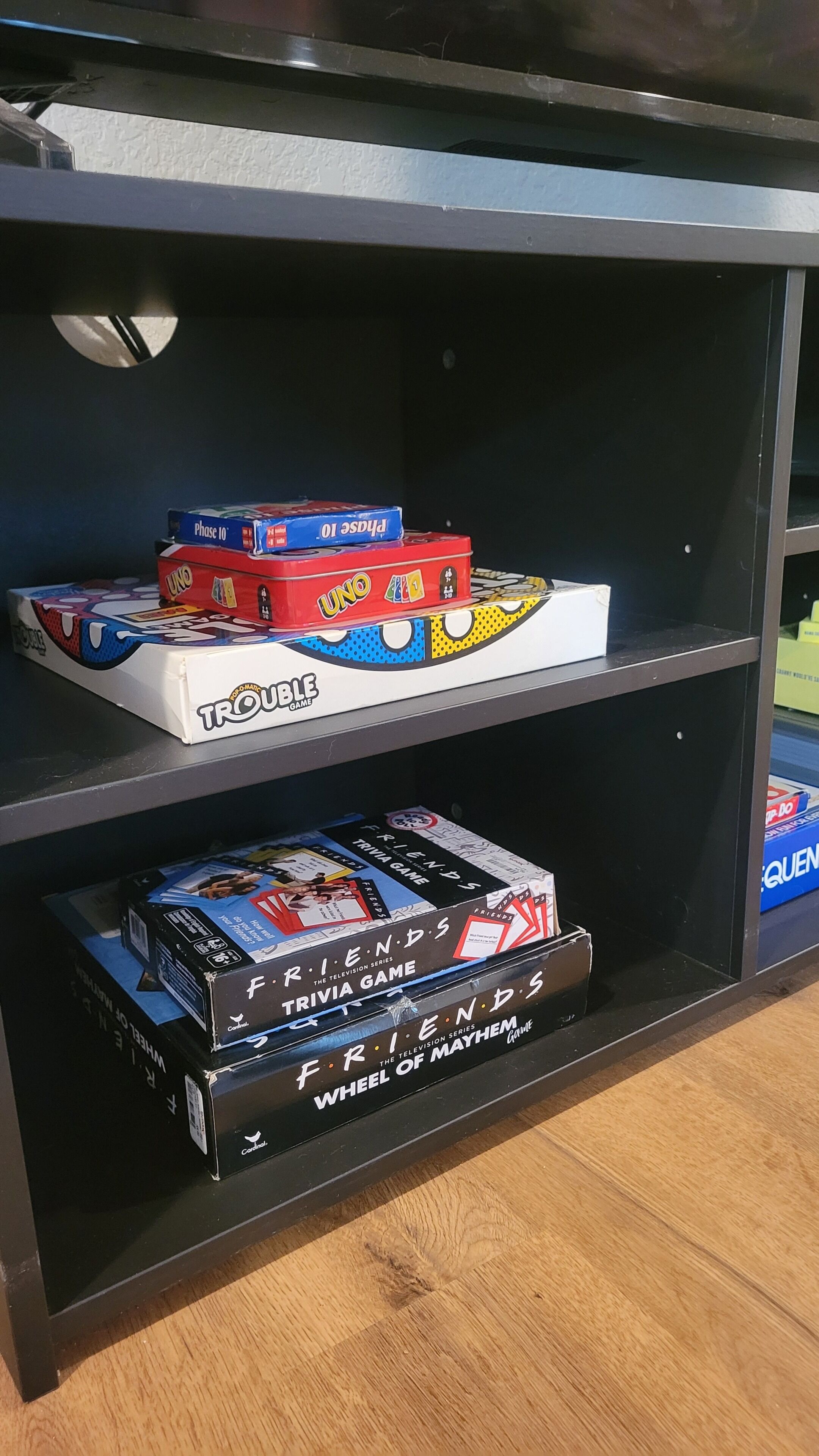 A shelf with board games including UNO, TRIVIA GAME, and FRIENDS SERIES.
