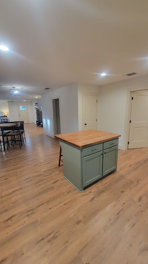 Una cocina amplia con encimera y armarios de madera, un comedor con mesa y sillas, y un pasillo que conduce a otras habitaciones.
