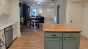 A spacious kitchen with wooden flooring, a central island, and a dining area with a table and chairs. - Delightful 2-bedroom house in Stephenville just STEPS from Tarleton State (Stephenville)