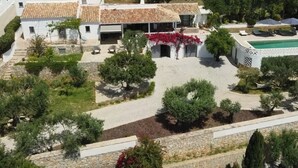 Une cour avec une piscine, des murs en pierre et un bâtiment blanc doté d’un toit en tuiles.