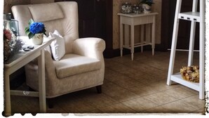 Ein Zimmer mit einem beigefarbenen Sessel, einem kleinen Tisch mit Blumenvase, einer weißen Leiter und zwei Türen.