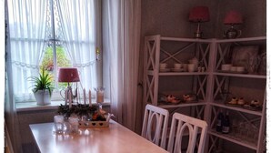 Ein Essbereich mit Tisch, Stühlen, einer Speisekammer und einem Fenster mit Vorhängen.