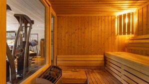 A sauna with wooden walls and benches, a steam room, and exercise equipment visible through the window. - Villa Bali sur la Côte d'Azur - Oasis among olive trees (Valbonne)
