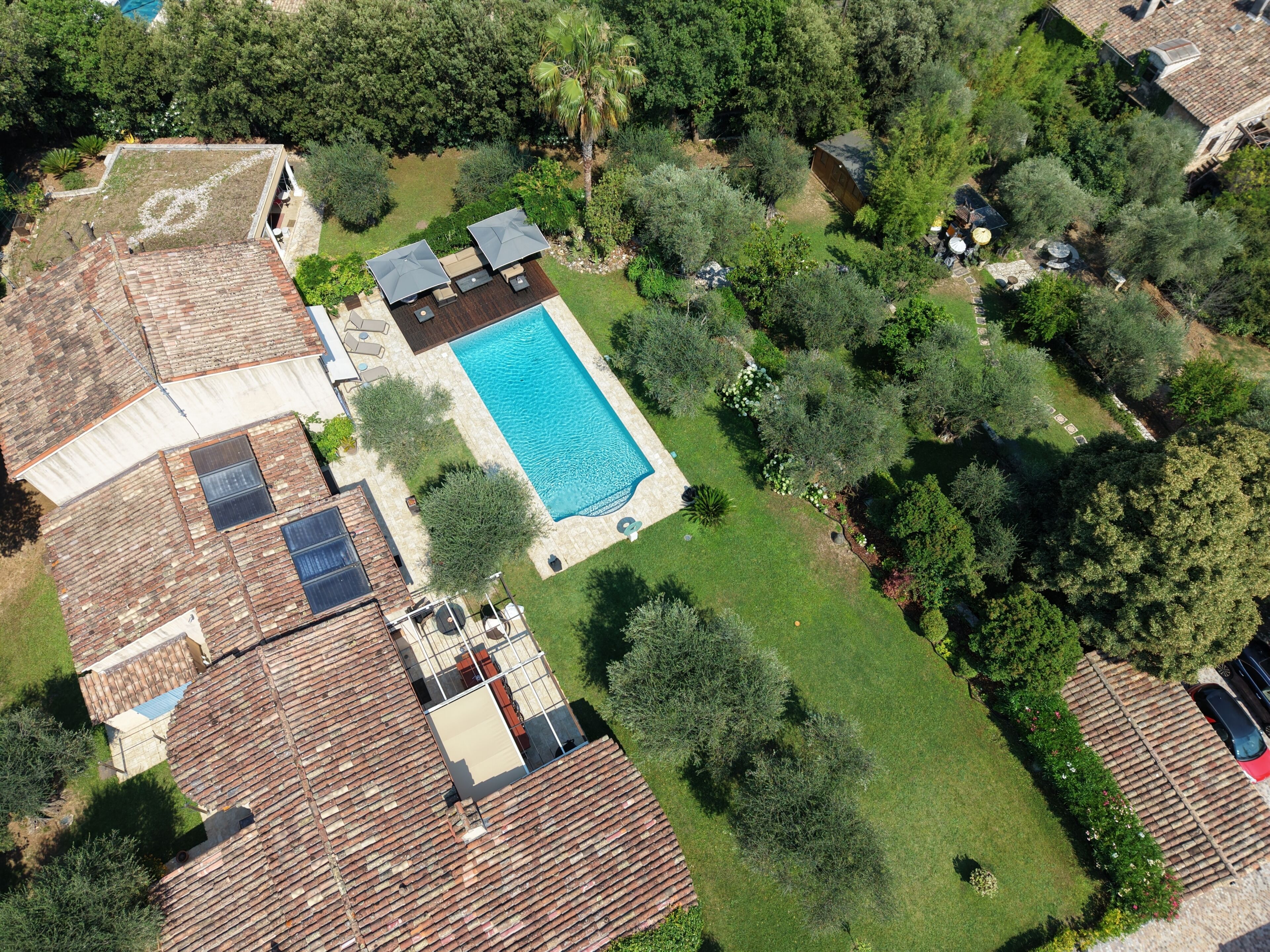 An aerial view of a residential property with a swimming pool, patio area, and surrounding greenery.