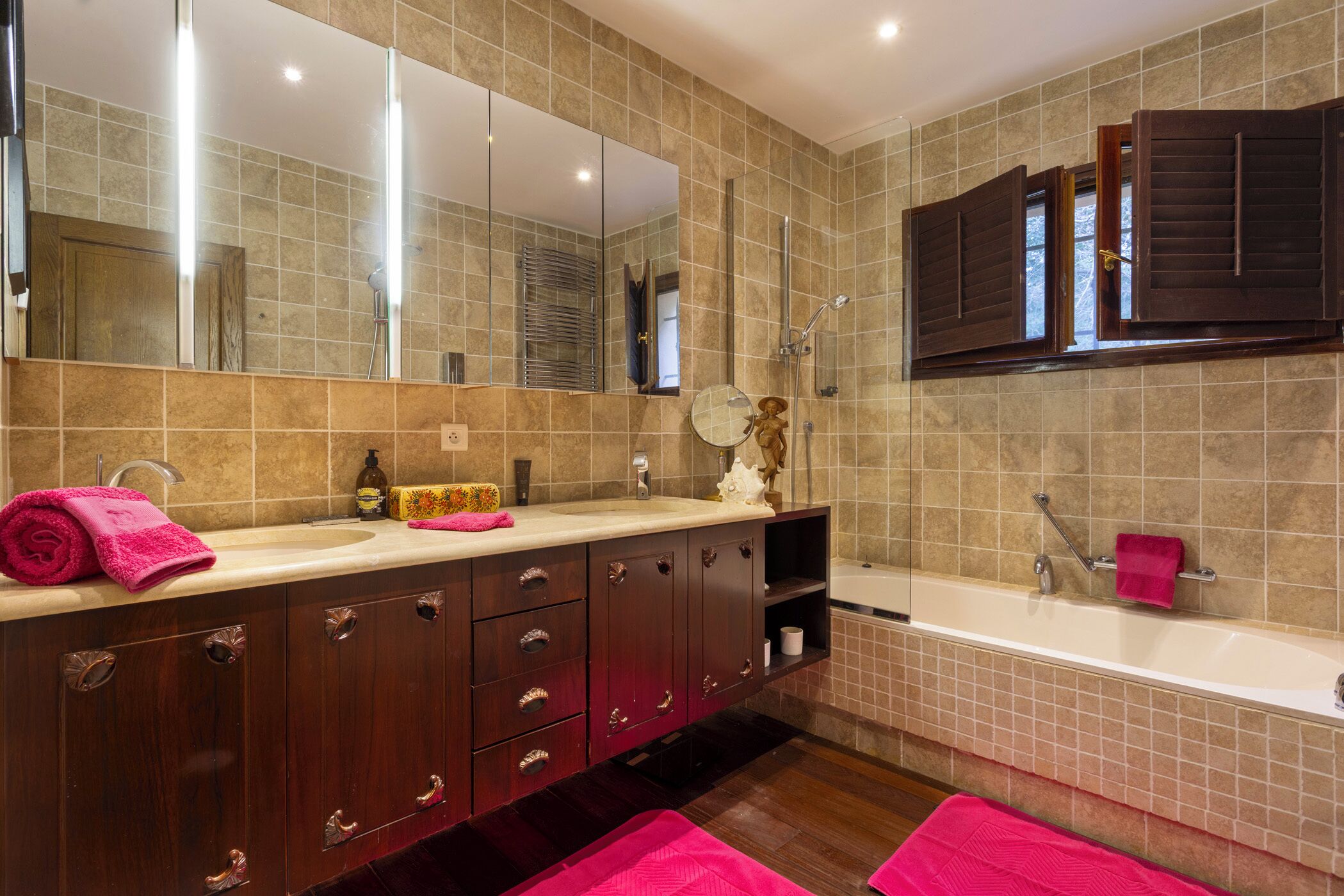 A bathroom with a large mirror, a bathtub, and a vanity with a sink.