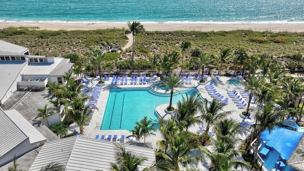 A resort with a swimming pool, lounge chairs, and a beach view. - First Floor Condo on Golf Course Near Beach (Fort Pierce)