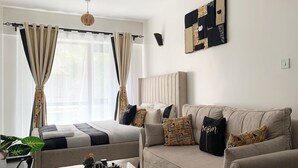 Een moderne woonkamer met een bank, een salontafel en een bed met gordijnen.
