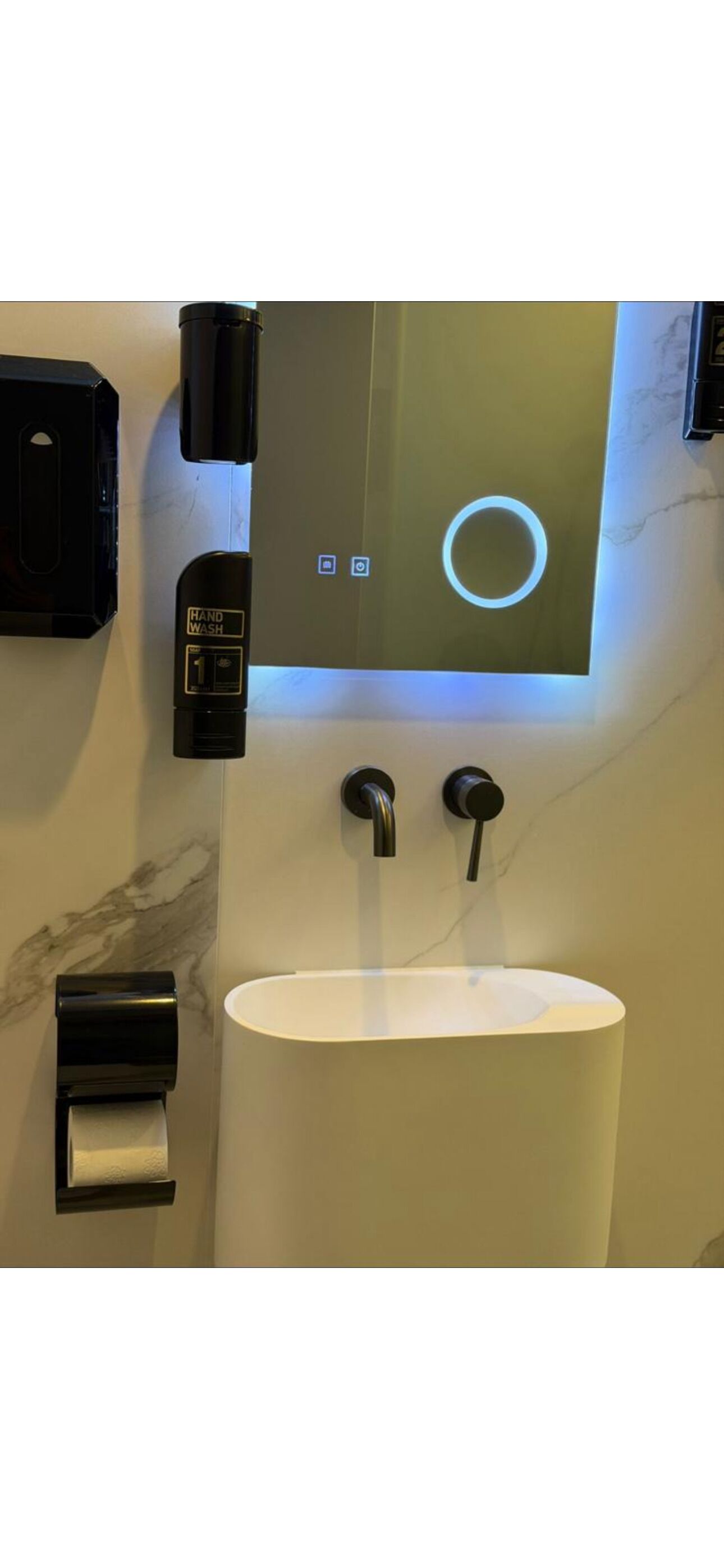 Un baño moderno con lavamanos integrado, estación para lavado de manos y dispensador de papel higiénico.