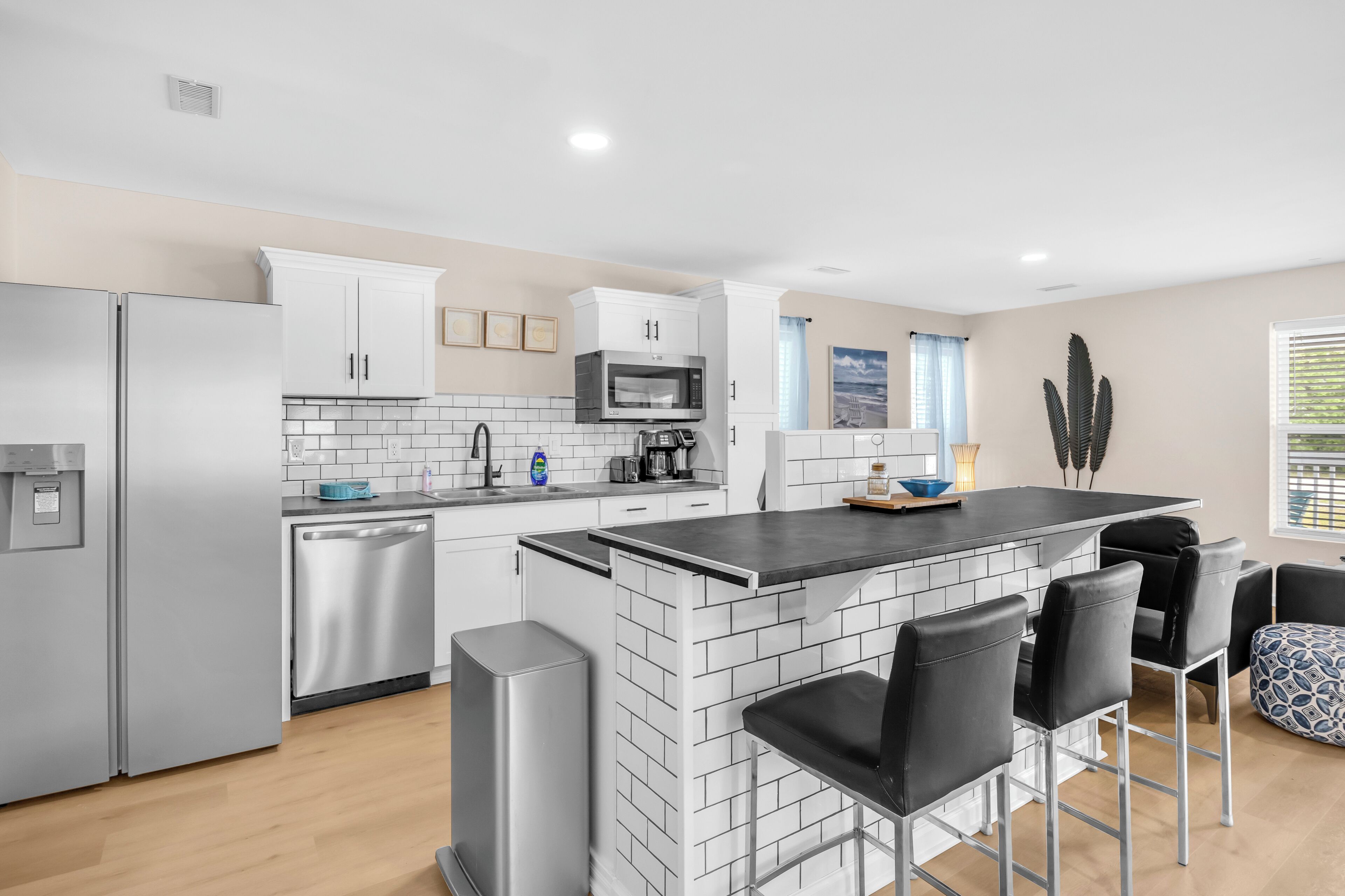 Une cuisine moderne dotée d’appareils électroménagers en acier inoxydable, d’un îlot central avec des tabourets de bar et offrant une vue sur la ville par la fenêtre.