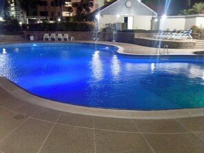 A swimming pool with a tiled deck and lounge chairs.