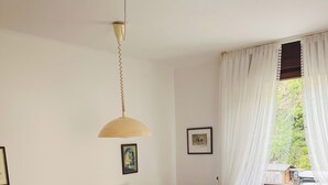 Un lit double avec un cadre en bois, une table de chevet, une lampe, un radiateur et une fenêtre avec des rideaux légers.