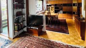Un salon comprenant un téléviseur, une bibliothèque et un coin repas avec des chaises et une table.