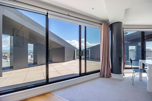 Ein modernes Hotelzimmer mit großen Schiebeglasfenstern, einem Balkon und einem Essbereich.