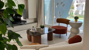 A modern living room with a sofa, a red chair, a glass coffee table, and a TV. - Fouka North Coast CL3-CH18-01 (Marsa Matrouh)