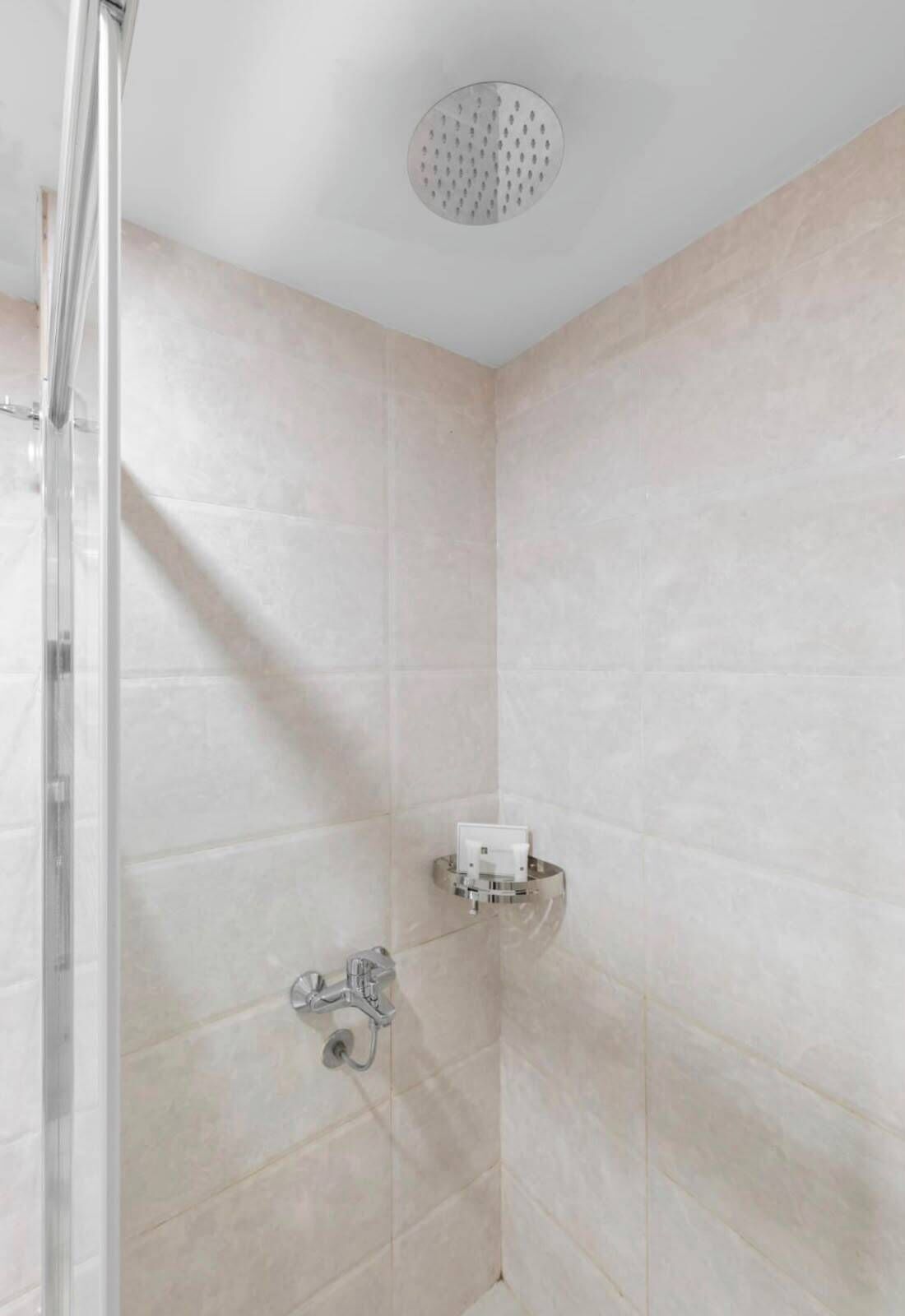 Una ducha con cerramiento de vidrio, grifo empotrado en la pared y ducha instalada en el techo.