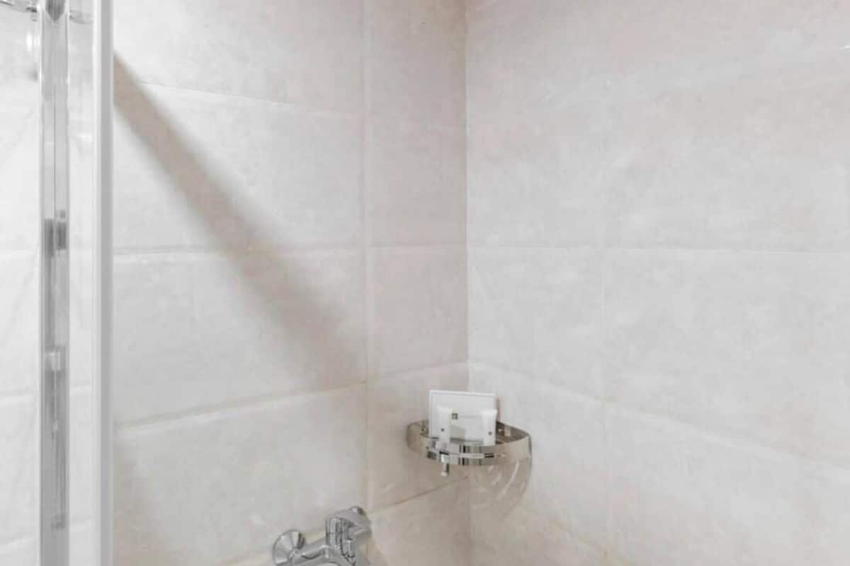 Una ducha con cerramiento de vidrio, grifo empotrado en la pared y ducha instalada en el techo.