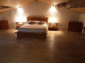 Ein Schlafzimmer mit einem hölzernen Bett, zwei Nachttischen und einer geneigten Decke.