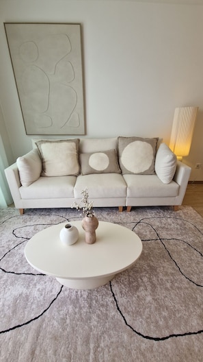 Ein Wohnzimmer mit einer Couch, einem runden Couchtisch und einem Gemälde an der Wand.