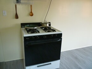 A kitchen with a stove, a pot on the burner, and wooden utensils hanging on the wall. - Peaceful 2-bedroom house with AC in charming Alhambra (Alhambra)